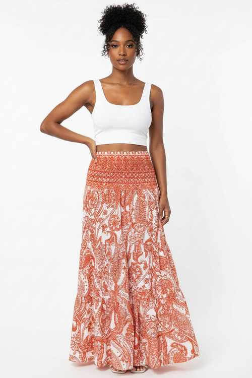 Jupe longue bohème Silhouette-Chic à imprimé paisley avec taille smockée et volants étagés - vue corps entier d'une mannequin avec main sur la hanche en pose confiante sur fond blanc studio, illustrant la silhouette bohème romantique, la longueur maxi flatteuse, la taille smockée confortable et l'attitude décontractée et élégante que procûre cette jupe