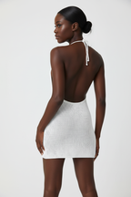 Mini robe crochet halter blanc - vue de dos spectaculaire révélant le design dos nu intégral, les bretelles halter ornées de perles artisanales qui se nouent élégamment dans le dos, et la ligne épurée de la silhouette mini - Détail du laçage halter sophistiqué - Style premium Black-Coat