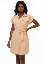 Robe chemise mini boutonnée col chemisier pointu avec poche poitrine patch, boutonnage frontal complet et ceinture nouée sculpturale en abricot beige chaud - vue de face complète sur fond blanc studio montrant la silhouette élégante et féminine, le tissu 100% polyester en abricot beige doux et lumineux - Mannequin en pose confiante et estivale - Collection mode féminine accessible premium Black-Coat