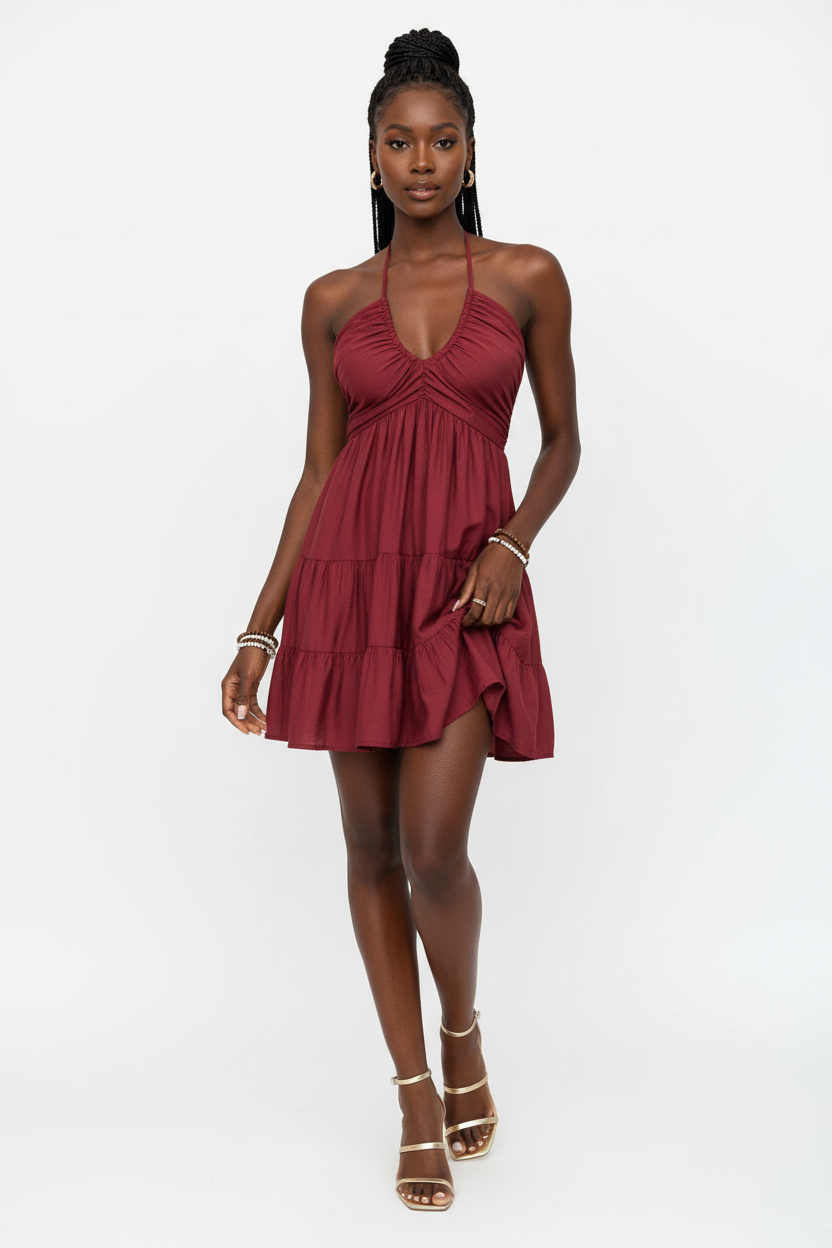 Robe mini halter smockée bordeaux avec col V profond à fronces empire, dos smocké ajustable avec laçage halter et trois niveaux de volants étagés - vue de face complète sur fond blanc studio montrant la silhouette romantique et féminine, le tissu 100% polyester léger en bordeaux profond et passionné - Mannequin en pose estivale élégante - Collection mode féminine accessible premium Black-Coat