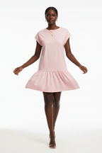 Robe t-shirt mini col rond à manches cap en rose blush en mouvement sur fond blanc studio - pose dynamique révélant la légèreté et le mouvement gracieux du volant bas - Style casual chic en action - Collection premium Black-Coat