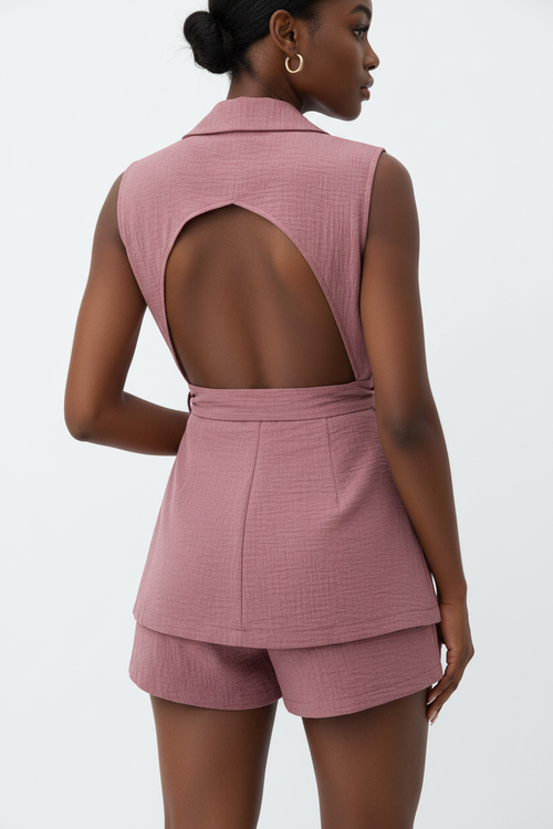 Vue arrière de l'ensemble 2 pièces blazer sans manches rose poudré sur fond blanc studio - dos révélant la coupe élégante du blazer, le nœud de la ceinture nouée dans le dos, et le short assorti en rose poudré - Détail du design chic et féminin - Style premium Silhouette-Chic