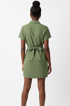 Vue arrière de la robe chemise mini boutonnée col chemisier en vert militaire sur fond blanc studio - dos révélant le nœud de la ceinture nouée sculpturale dans le dos et la longueur mini élégante - Détail du design safari chic - Style premium Black-Coat