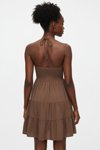 Vue arrière de la robe mini halter smockée marron mocha sur fond blanc studio - dos révélant le smocké ajustable sophistiqué, le laçage halter élégant dans la nuque, et les trois niveaux de volants étagés en marron mocha chaleureux - Détail du design romantique et enveloppant - Style premium Black-Coat
