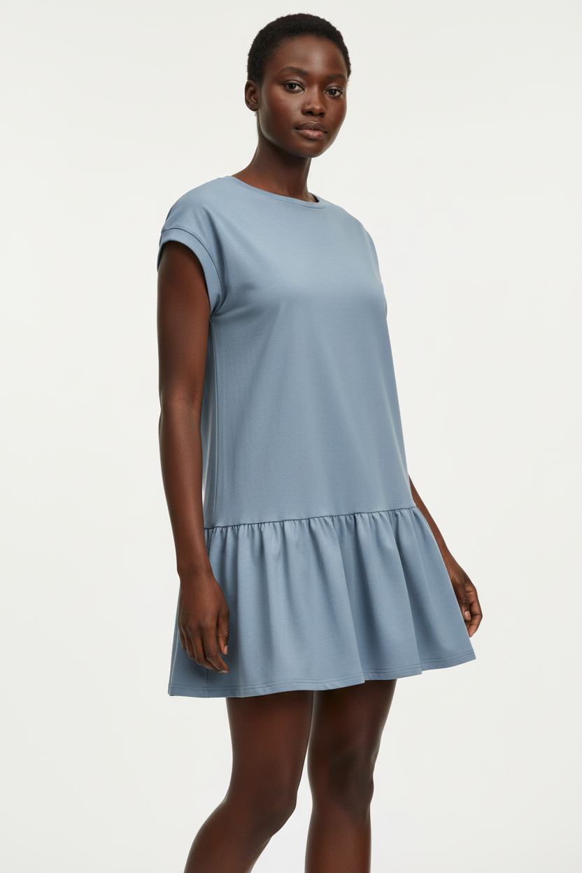 Vue trois-quarts de la robe t-shirt mini col rond à manches cap en bleu français sur fond blanc studio - angle mettant en valeur les manches cap courtes qui dégagent les épaules et le volant bas à taille basse romantique - Détail de la construction haut de gamme - Style éditorial Black-Coat