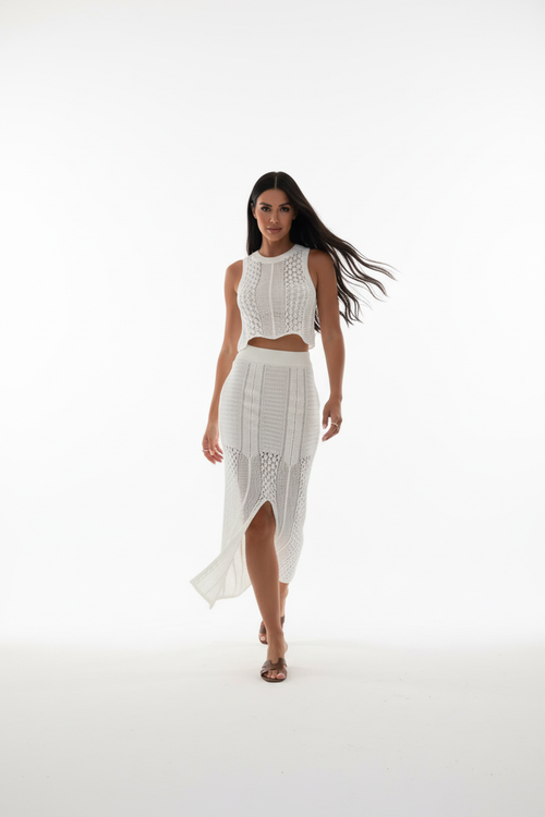 "Ensemble deux pièces crochet blanc - en marche mouvement naturel montrant la jupe midi crochet avec fente centrale qui s'ouvre en marchant, crop top ajusté, silhouette dynamique, texture crochet ajourée, fond blanc studio Silhouette-Chic"