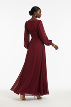 Vue de dos de la robe maxi chiffon rouge bordeaux ardent à manches ballon dramatiques en mousseline transparente — tombé fluide révélant le volume sculptural des manches, la taille empire fronc\u00e9e et la jupe évasée capturant la lumière avec une intensité ardente et romantique — bijoux dorés, sandales nude — Silhouette-Chic