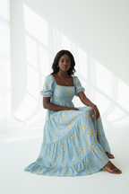  Robe Maxi Étagée à Imprimé Marguerites Black-Coat bleu clair - pose assise montrant le drapé élégant des volants étagés et le confort