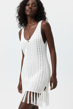 Gros plan détaillé du haut de la robe crochet blanc - vue rapprochée montrant la texture artisanale du tricot ajouré openwork en coton 100%, les découpes sophistiquées, les détails franges bohèmes, et les finitions premium de cette robe cover-up estivale - Détail de la construction haut de gamme - Style premium Black-Coat